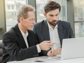 Zwei Männer diskutieren vor einem Laptop